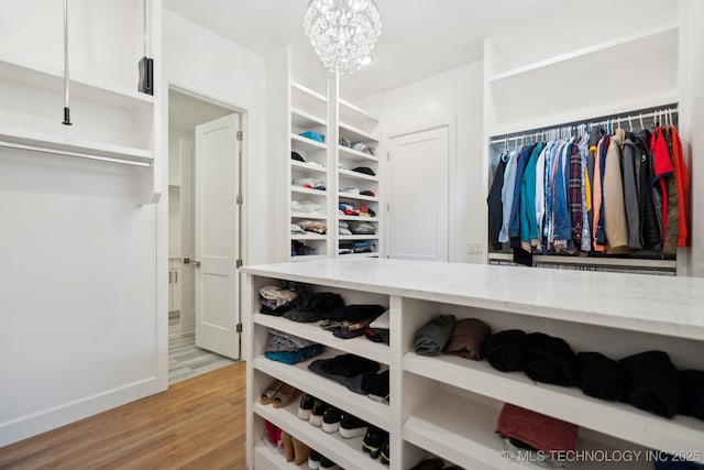 spacious closet featuring hardwood / wood-style flooring and a notable chandelier