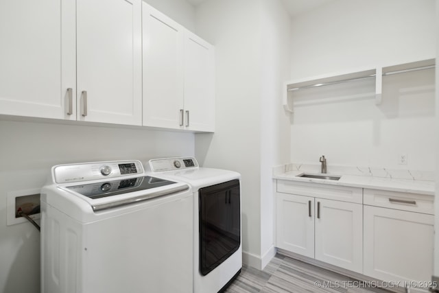 washroom featuring separate washer and dryer, sink, cabinets, and light wood-type flooring