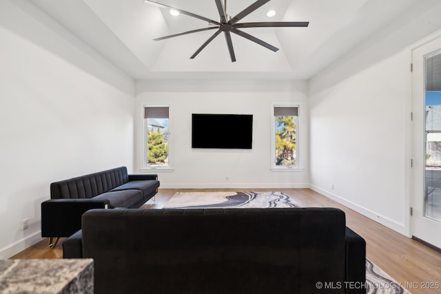 living room with a raised ceiling, wood-type flooring, lofted ceiling, and ceiling fan