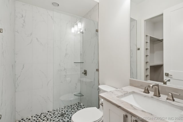 bathroom featuring vanity, tiled shower, and toilet