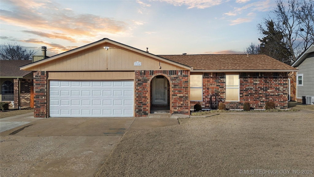 ranch-style house featuring central air condition unit and a garage