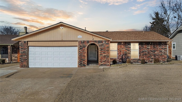 ranch-style house featuring central air condition unit and a garage