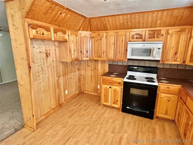 kitchen with a textured ceiling, wood walls, light hardwood / wood-style floors, and white appliances