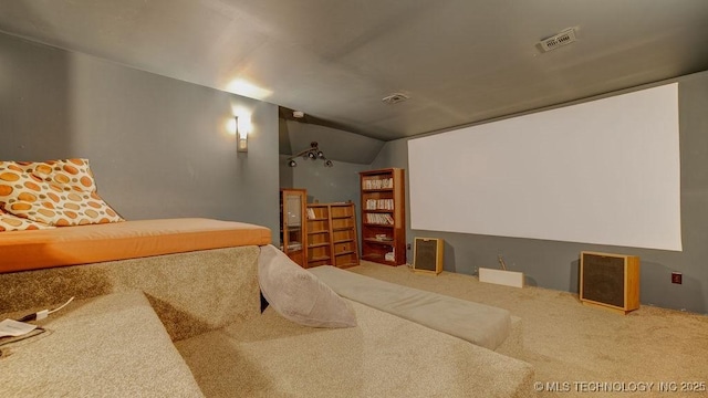 cinema with carpet flooring, visible vents, and vaulted ceiling