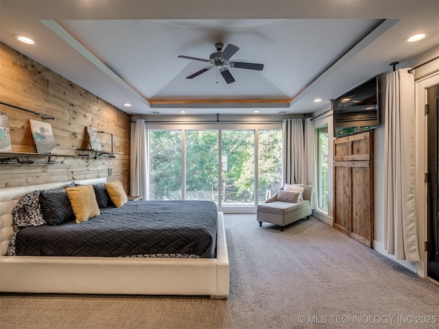 bedroom featuring carpet floors, recessed lighting, a tray ceiling, and wooden walls