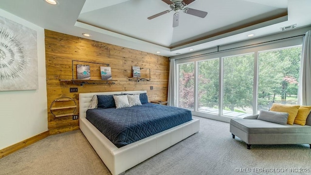 bedroom featuring recessed lighting, a raised ceiling, carpet, and wooden walls