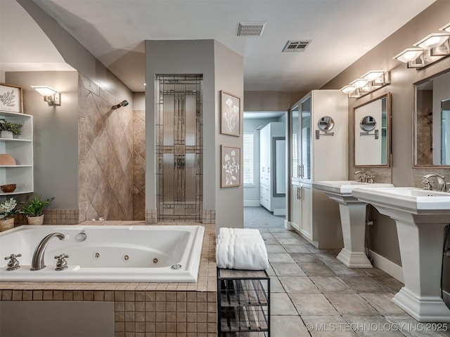bathroom featuring a whirlpool tub, a tile shower, and visible vents