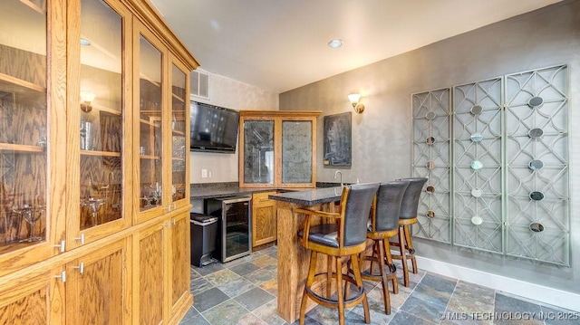 bar with indoor wet bar, wine cooler, stone finish floor, and visible vents