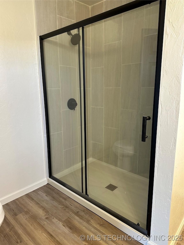 bathroom with wood-type flooring and a shower with door