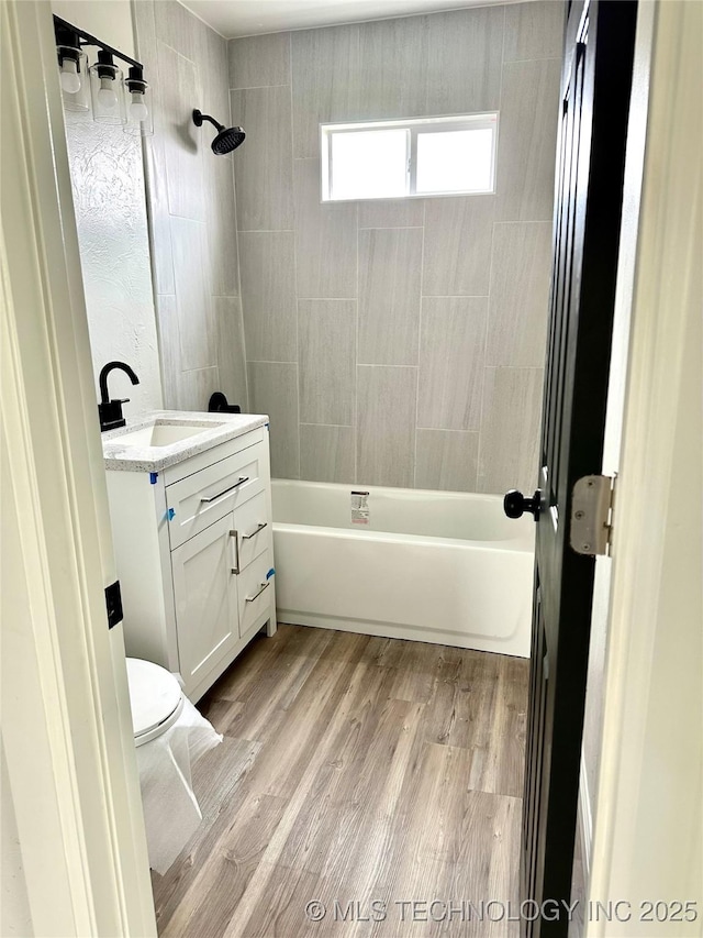 full bathroom featuring tiled shower / bath, vanity, wood-type flooring, and toilet