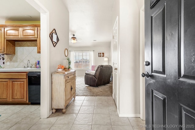 kitchen with tasteful backsplash, ceiling fan, sink, light tile patterned floors, and black dishwasher