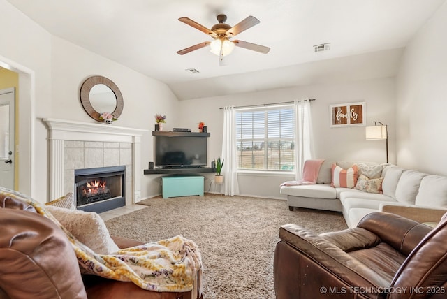 living room with a tiled fireplace, ceiling fan, carpet, and lofted ceiling