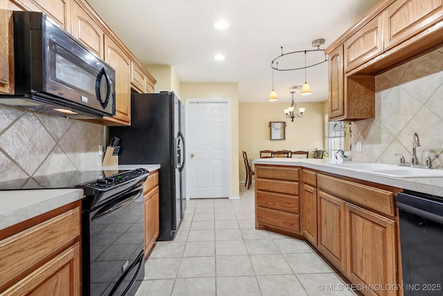 kitchen with tasteful backsplash, sink, black appliances, hanging light fixtures, and light tile patterned flooring