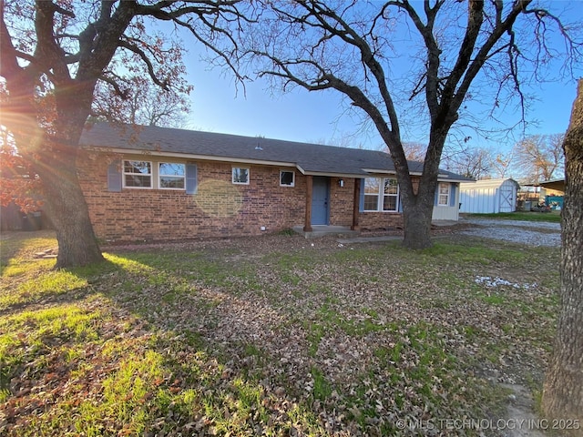 ranch-style home with a front yard and a storage shed