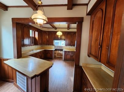 kitchen featuring beamed ceiling, pendant lighting, and light wood-type flooring