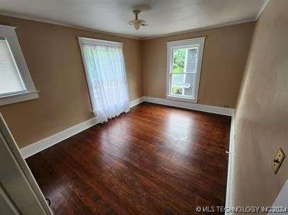 spare room with dark hardwood / wood-style floors and crown molding