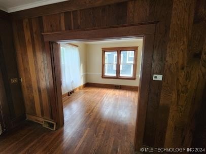 spare room featuring dark hardwood / wood-style floors, ornamental molding, and wooden walls