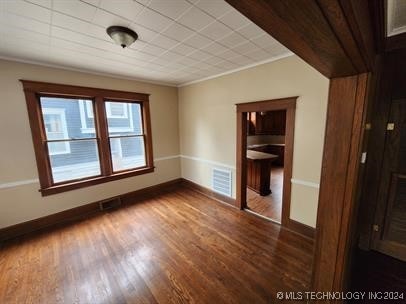 spare room featuring wood-type flooring and ornamental molding