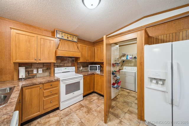 kitchen with custom range hood, vaulted ceiling, washer / dryer, white appliances, and a sink