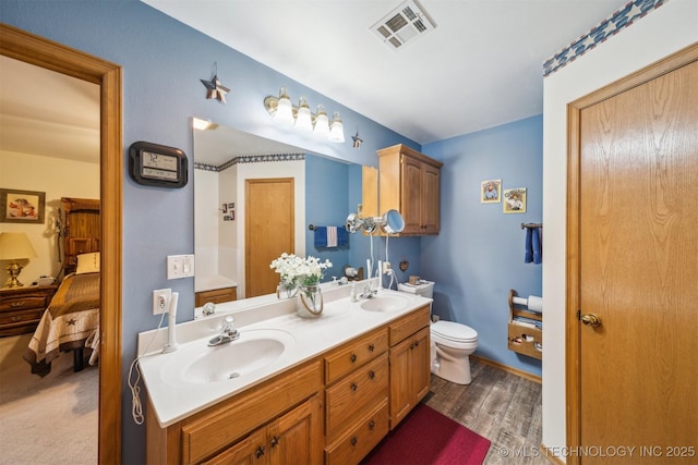 bathroom with a sink, visible vents, toilet, and double vanity