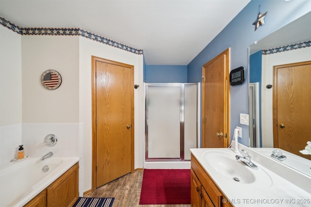 bathroom featuring vanity, a bath, wood finished floors, and a stall shower