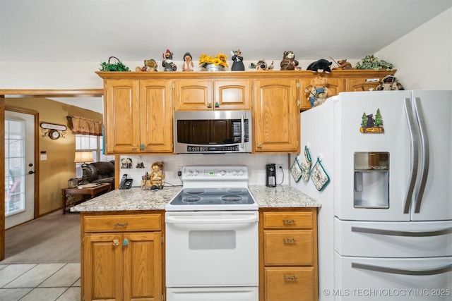 kitchen featuring light carpet, light stone counters, backsplash, white appliances, and light tile patterned floors