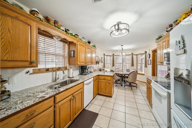 kitchen with backsplash, light tile patterned floors, a wealth of natural light, white appliances, and a sink