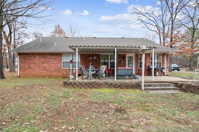 back of house with brick siding, a shingled roof, and a patio