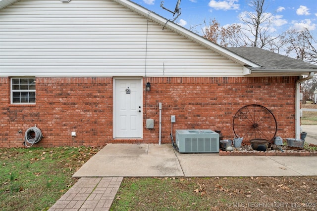 rear view of property featuring central air condition unit, brick siding, and a shingled roof