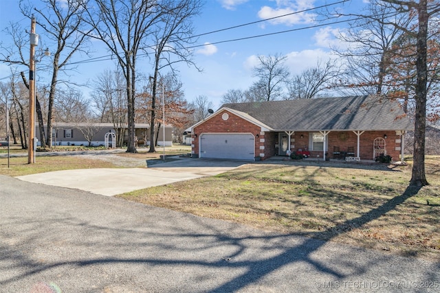 view of front of house with brick siding, a front lawn, concrete driveway, covered porch, and a garage