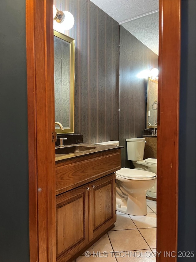 bathroom with tile patterned flooring, vanity, toilet, and a textured ceiling