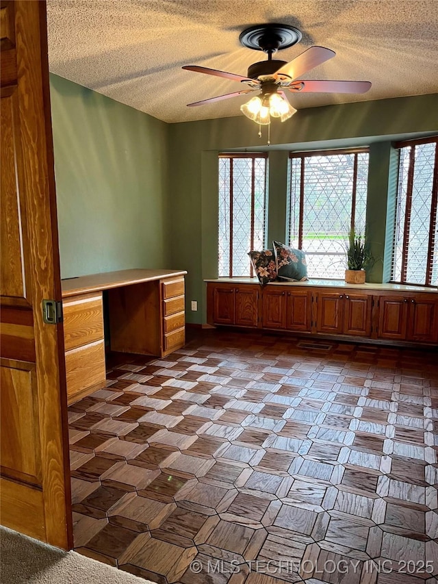 empty room featuring ceiling fan and a textured ceiling