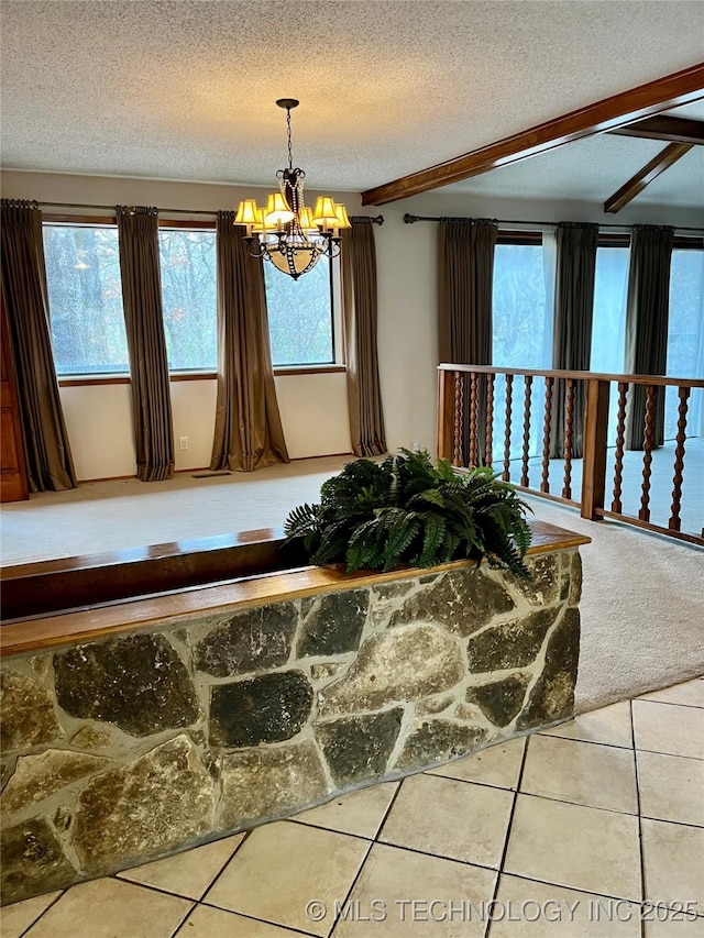 interior details featuring carpet flooring, a notable chandelier, beam ceiling, and a textured ceiling