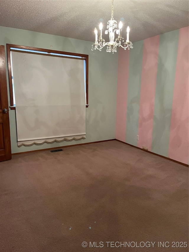 carpeted empty room featuring a notable chandelier and a textured ceiling