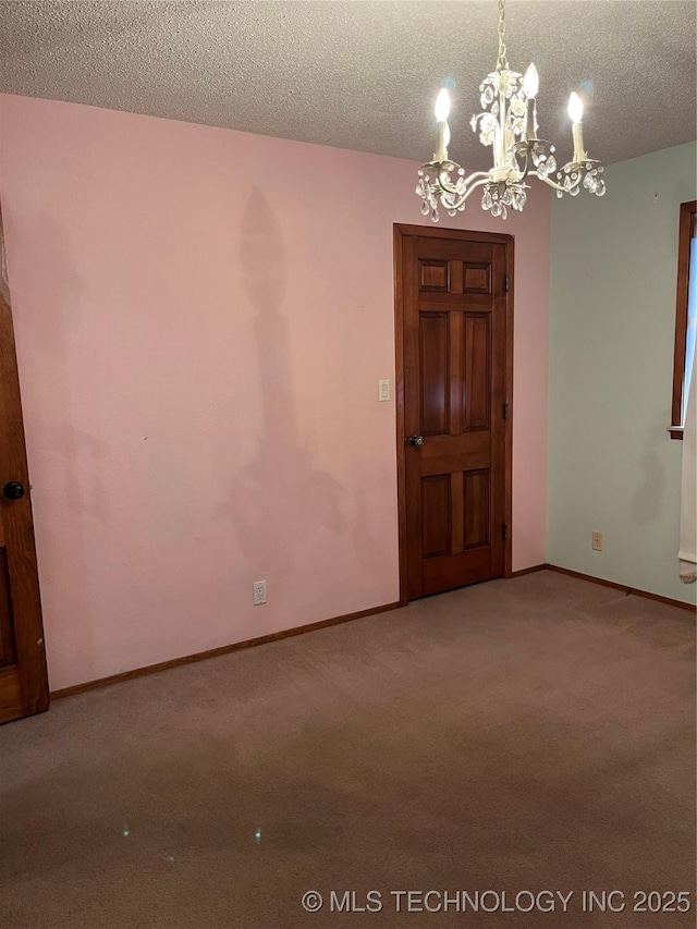 carpeted spare room featuring a textured ceiling, baseboards, and an inviting chandelier