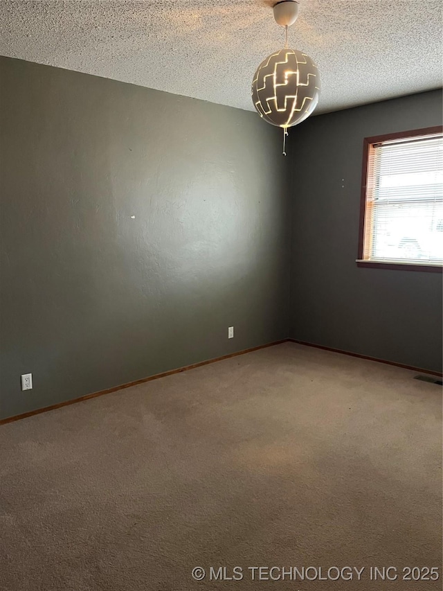 carpeted spare room with a textured ceiling, baseboards, and visible vents