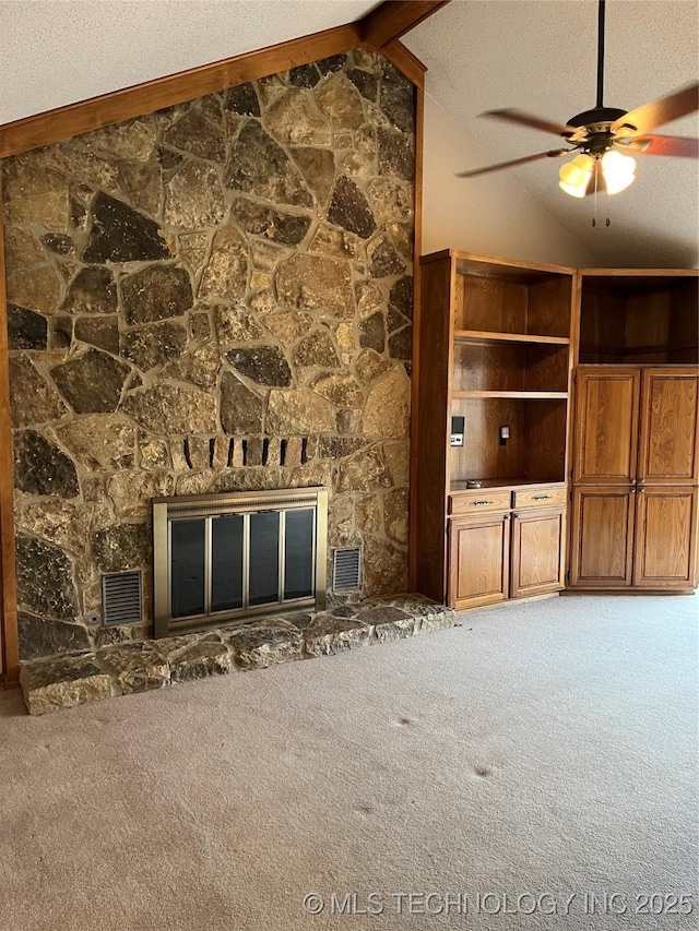 unfurnished living room featuring carpet, vaulted ceiling with beams, a stone fireplace, and ceiling fan