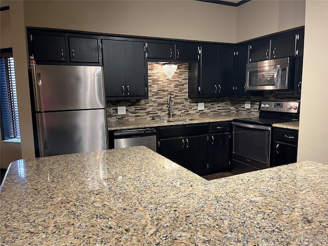 kitchen with light stone countertops, sink, appliances with stainless steel finishes, and tasteful backsplash