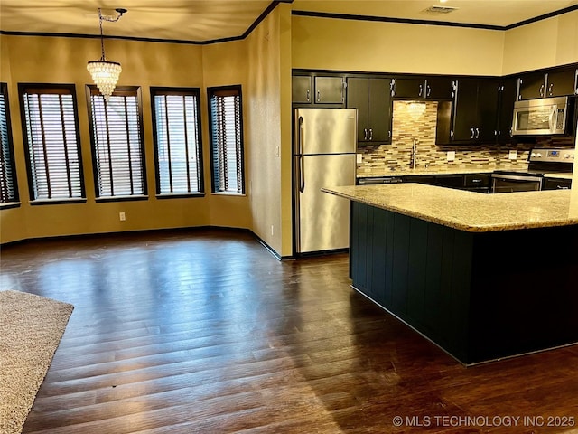 kitchen with stainless steel appliances, a wealth of natural light, ornamental molding, and tasteful backsplash