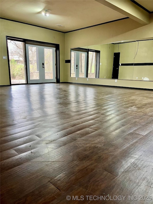 spare room featuring french doors, beamed ceiling, and wood-type flooring