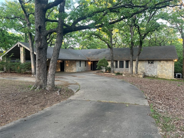 ranch-style home with aphalt driveway and stone siding
