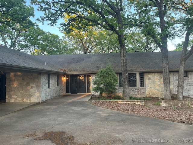 single story home featuring stone siding and a shingled roof