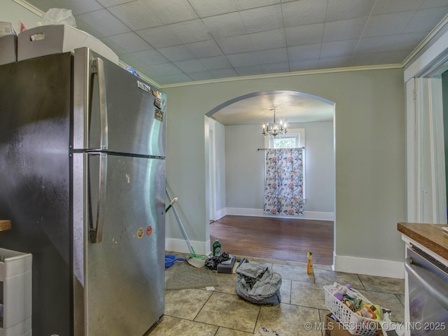 kitchen with stainless steel appliances, an inviting chandelier, crown molding, decorative light fixtures, and light tile patterned floors