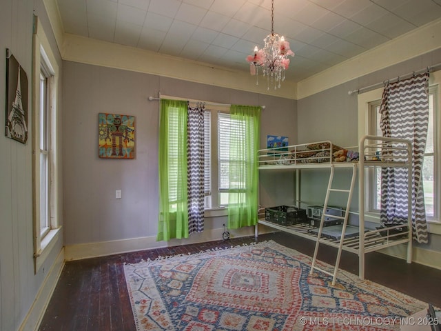 bedroom with wood-type flooring and an inviting chandelier