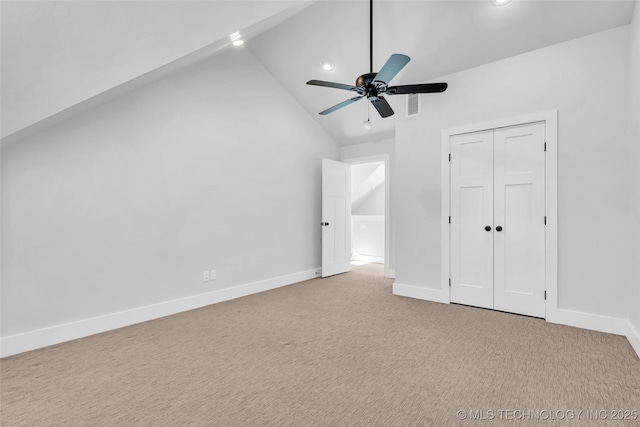 unfurnished bedroom with ceiling fan, a closet, light carpet, and vaulted ceiling