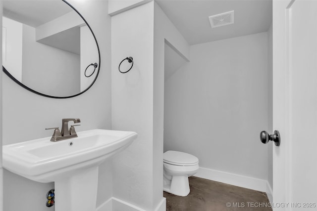 bathroom with sink, concrete flooring, and toilet