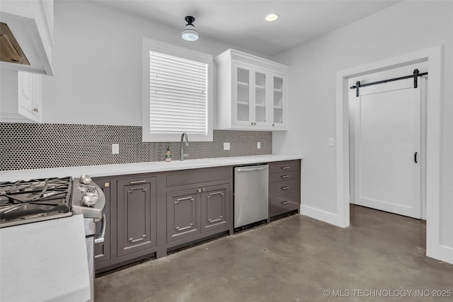 kitchen with gray cabinetry, sink, a barn door, concrete floors, and white cabinetry