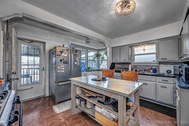 kitchen with gray cabinets, stainless steel fridge, dark parquet flooring, and stove