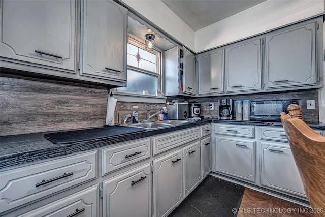 kitchen with gray cabinetry, sink, and tasteful backsplash