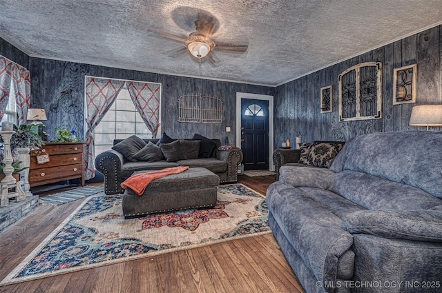 living room featuring hardwood / wood-style flooring, ceiling fan, and wooden walls